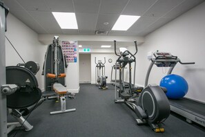 A gym with various exercise equipment including a treadmill, elliptical, and weight machines.