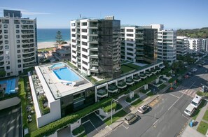 A modern hotel with multiple floors, a rooftop pool, and a view of the beach. - Marvellous Mount Apartment with pool, gym & beach (Mount Maunganui)