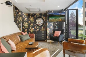 Een moderne woonkamer met een bank, fauteuil en een televisie aan de muur.