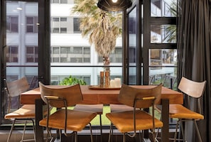 A dining area with a wooden table and four chairs, a potted plant, and a modern pendant light.