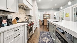A modern kitchen with stainless steel appliances, a large island, and a view into the dining area. - Shared Amenities w/ LSV and Screened Porch (Santa Rosa Beach)