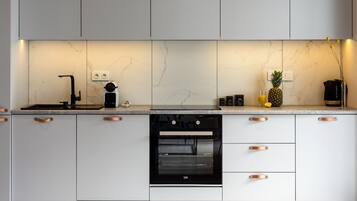 Eine moderne Küche mit weißen Schränken, einem schwarzen Backofen und einer Marmor-Spritzschutzwand.