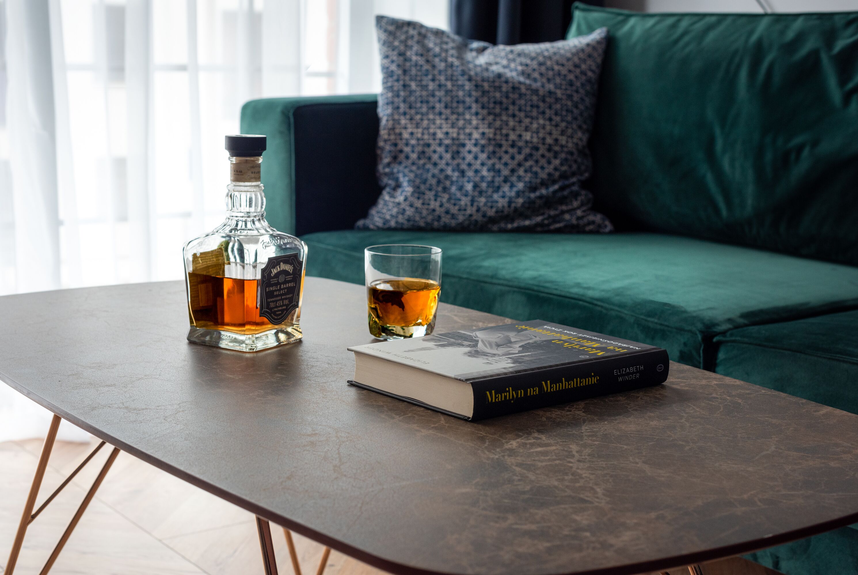 En bog med titlen 'Marilyn on Manhattan' og en flaske whisky på et bord.