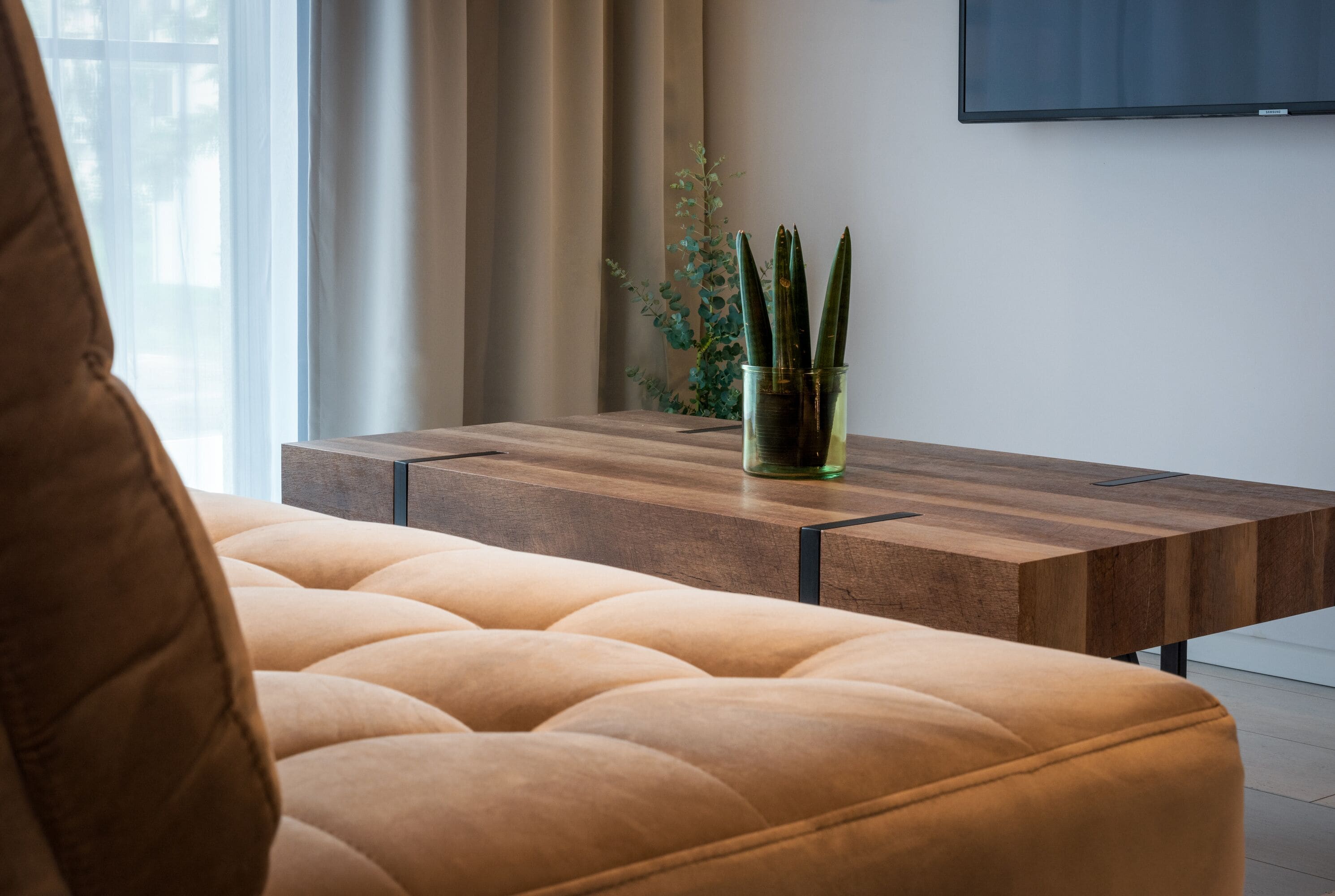 A modern living room with a tufted sofa, a wooden coffee table, and a potted plant.
