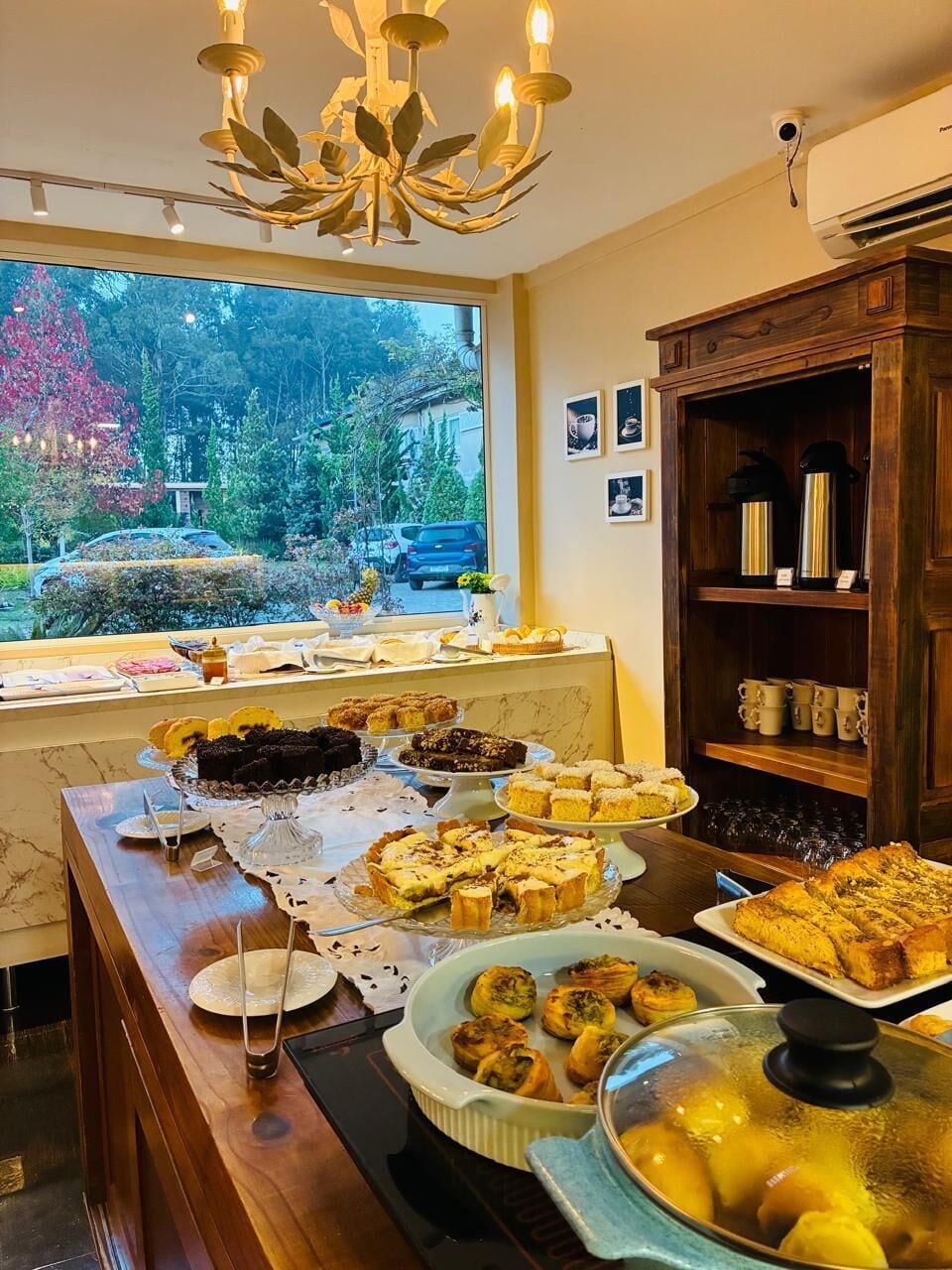 A buffet with various desserts and a view of trees outside.
