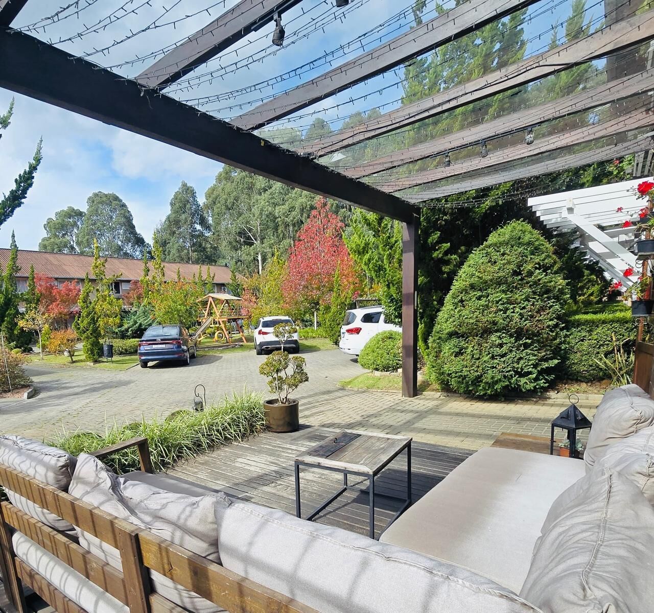 A covered outdoor seating area with a wooden bench, a small table, and a potted plant.