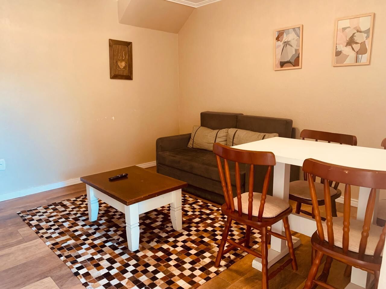 Ein Wohnzimmer mit einer Couch, einem kleinen Tisch und einem Esstisch mit Stühlen.