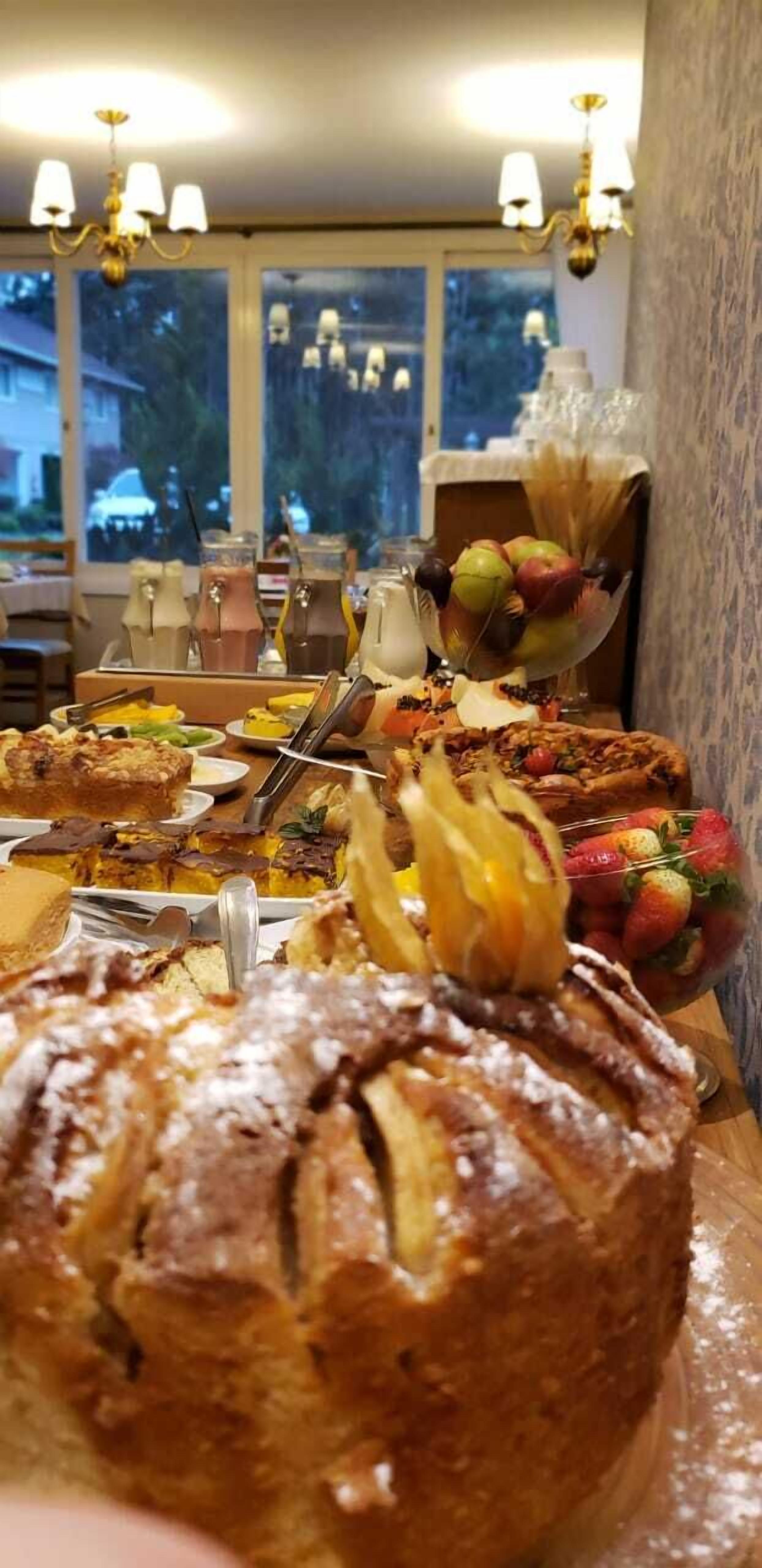 Una mesa de comedor con diversos postres y bebidas, un candelabro y una ventana que ofrece vistas al exterior.