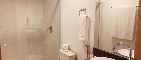 A bathroom with a glass-enclosed shower, a toilet, a sink with a mirror, and a towel rack.