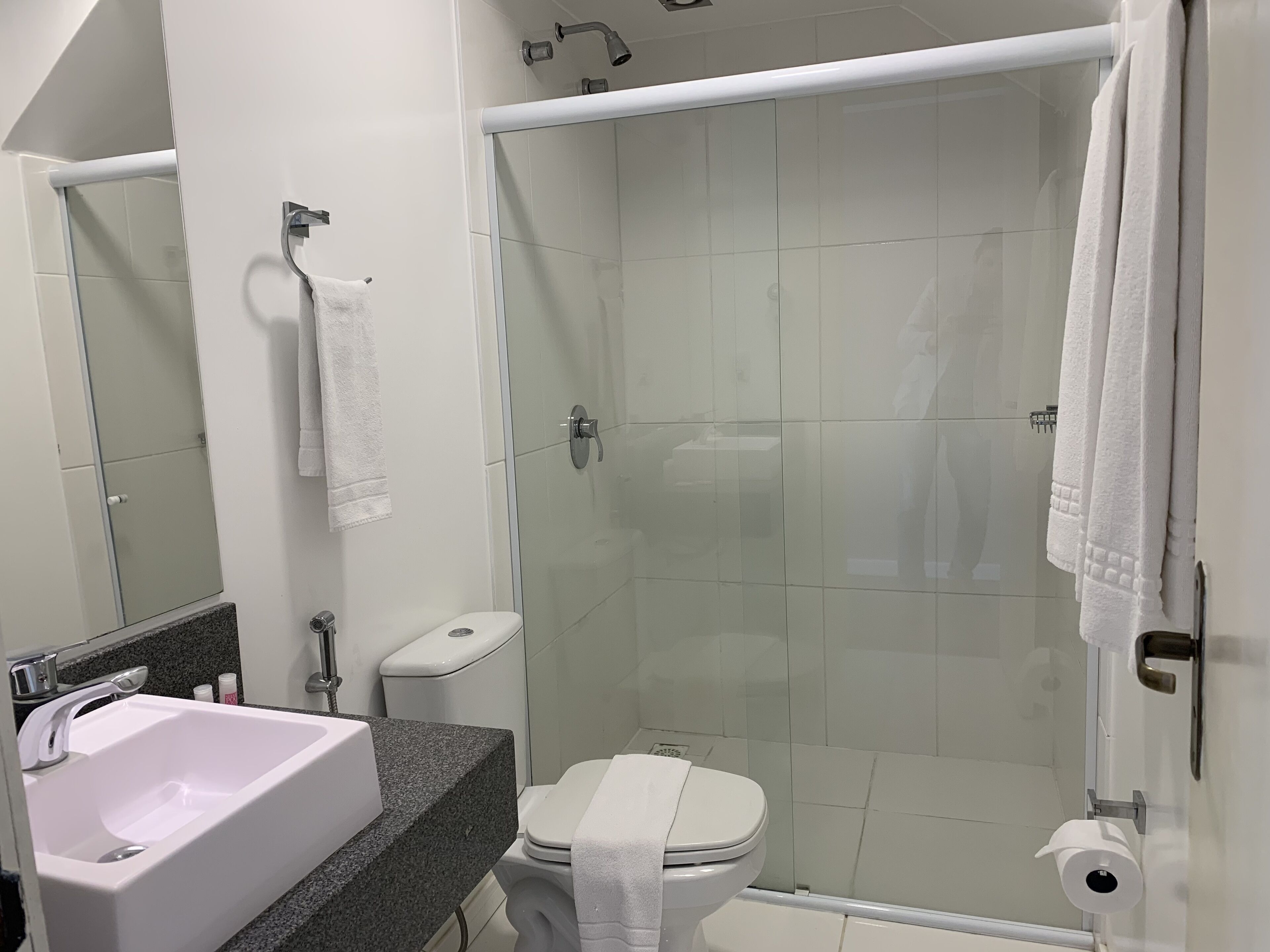 A modern bathroom with a white sink, toilet, and shower area.