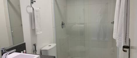 A modern bathroom with a white sink, toilet, and shower area.