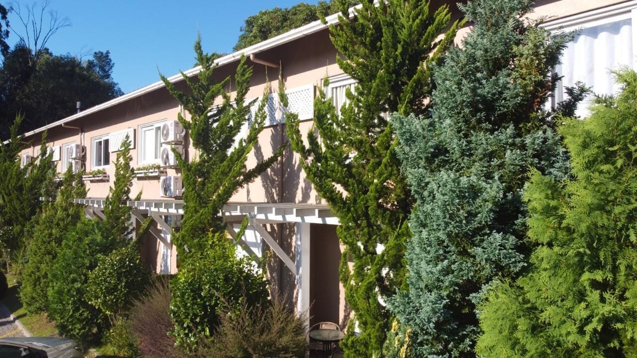 Una hilera de edificios de dos pisos con balcones, rodeados de abundante vegetación.