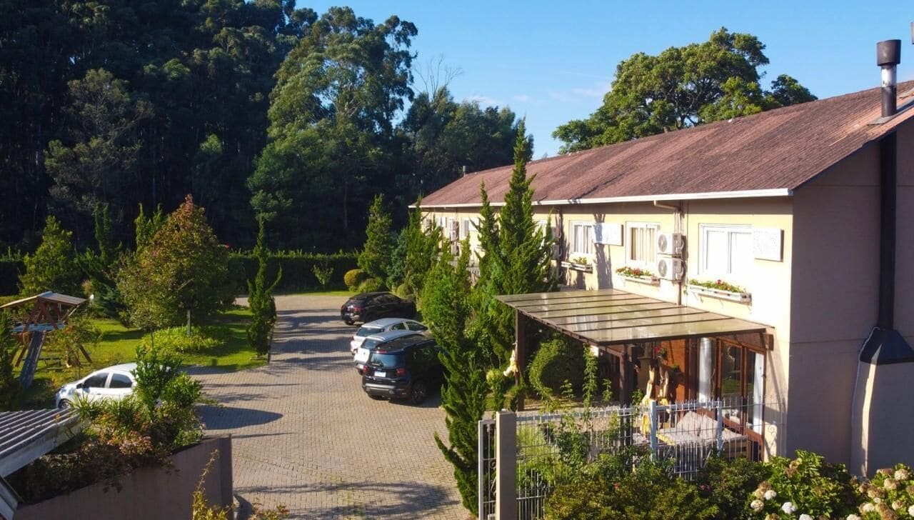 A building with a covered outdoor area, a paved driveway, and parked cars.