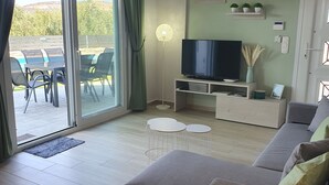 A modern living room with a sofa, a TV, and a dining area with chairs and a table. - NEW Villa Sheila with private pool and BBQ. (Rethymno, Crete)
