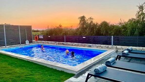 A rectangular swimming pool with a tiled edge, surrounded by a grassy area and a wooden fence. - NEW Villa Sheila with private pool and BBQ. (Rethymno, Crete)