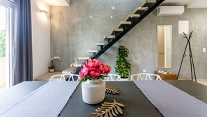 A modern dining area with a table set for two, a vase of flowers, and a staircase in the background. - VillaTango (Okrug Gornji)