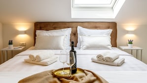 A neatly made bed with pillows, a bottle of wine, and glasses on a tray, with a skylight above. - VillaTango (Okrug Gornji)