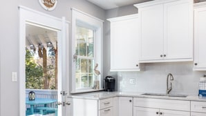 A modern kitchen with white cabinets, a stainless steel sink, and a coffee maker. - Prince's Folly! Walking Distance to Shops and Restaurants! (Folly Beach)