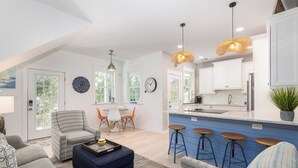 A modern living room with a sofa, ottoman, and a dining area with a table and chairs. - Prince's Folly! Walking Distance to Shops and Restaurants! (Folly Beach)