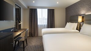 A hotel room with a bed, a desk, a chair, a TV, and a window with curtains. - Leonardo Hotel Chester (Chester)