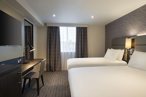 A hotel room with a bed, a desk, a chair, a TV, and a window with curtains. - Leonardo Hotel Chester (Chester)
