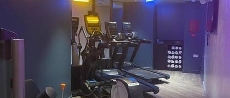 A gym with treadmills, weight machines, and a mirror.