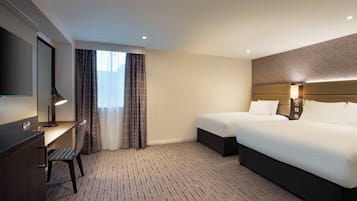 A hotel room with a bed, a desk, a chair, a TV, and a window with curtains.