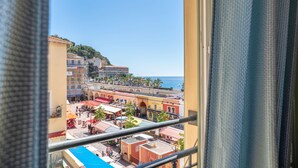 Une vue depuis un balcon donnant sur une ville côtière, avec ses bâtiments, sa plage et un ciel dégagé.