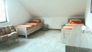 A small, well-lit room with two single beds, a wooden floor, a chair, and a bedside table with a lamp. - Large 90 sqm vacation apartment (Schönstedt)