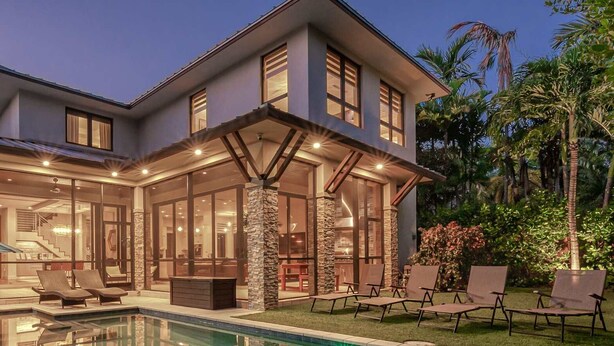 Una casa moderna con piscina, mobiliario exterior y un interior bien iluminado.