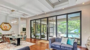 Amplia sala de estar con pared de vidrio, una mesa de comedor y un sofá.