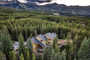 Ein zweistöckiges Haus, umgeben von dichtem Wald, mit freiem Blick auf die umliegenden Berge.