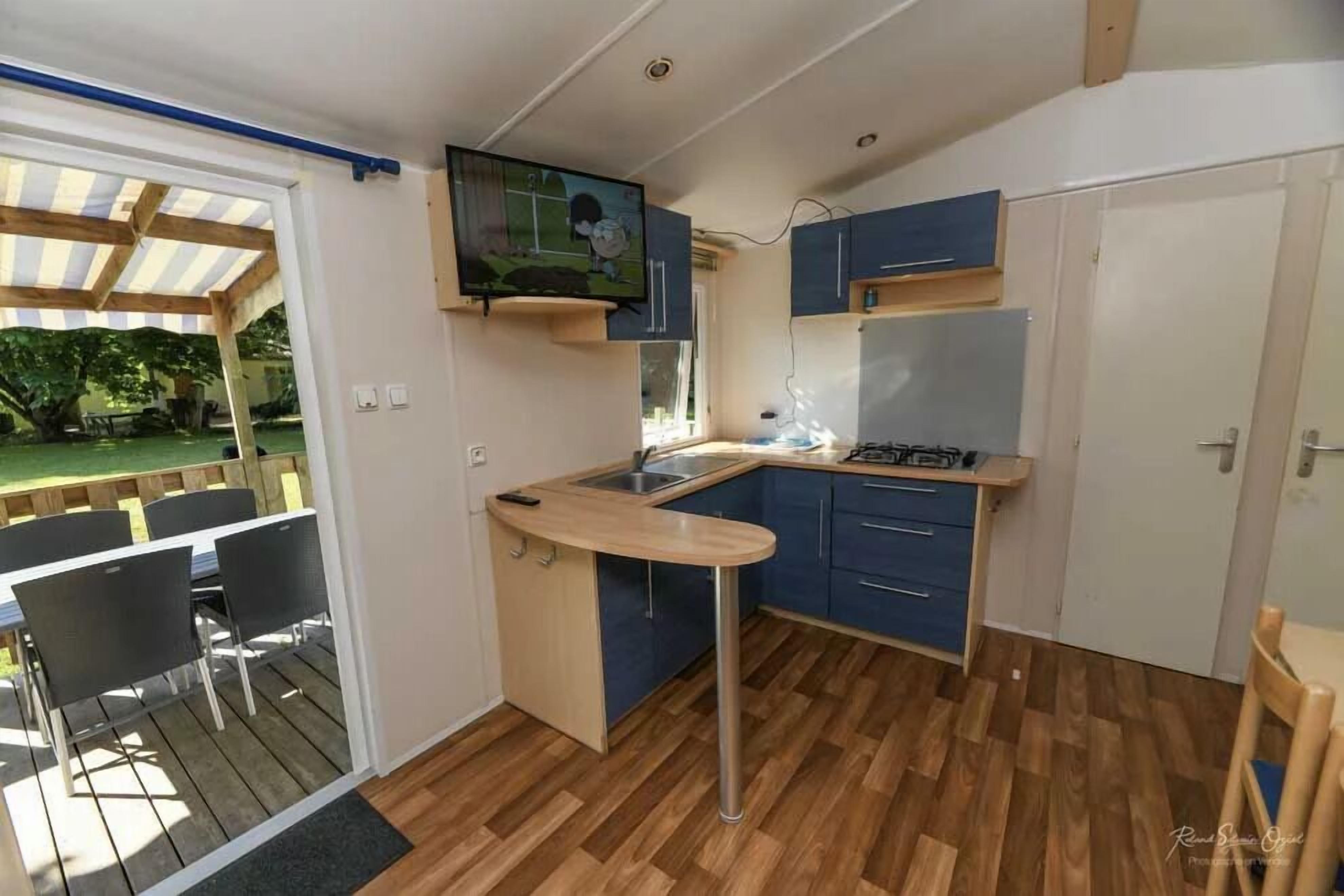 A compact kitchen with a built-in stove, blue cabinets, and a dining area with a table and chairs.