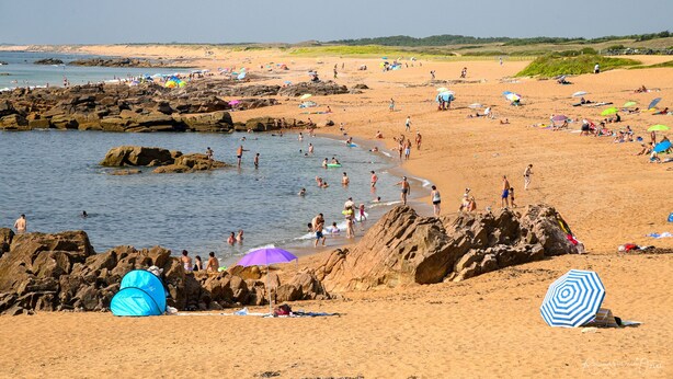 A beach with rocky areas, people swimming and sunbathing, and beach umbrellas. - Domaine Les Rousselieres (Les Sables-d'Olonne)