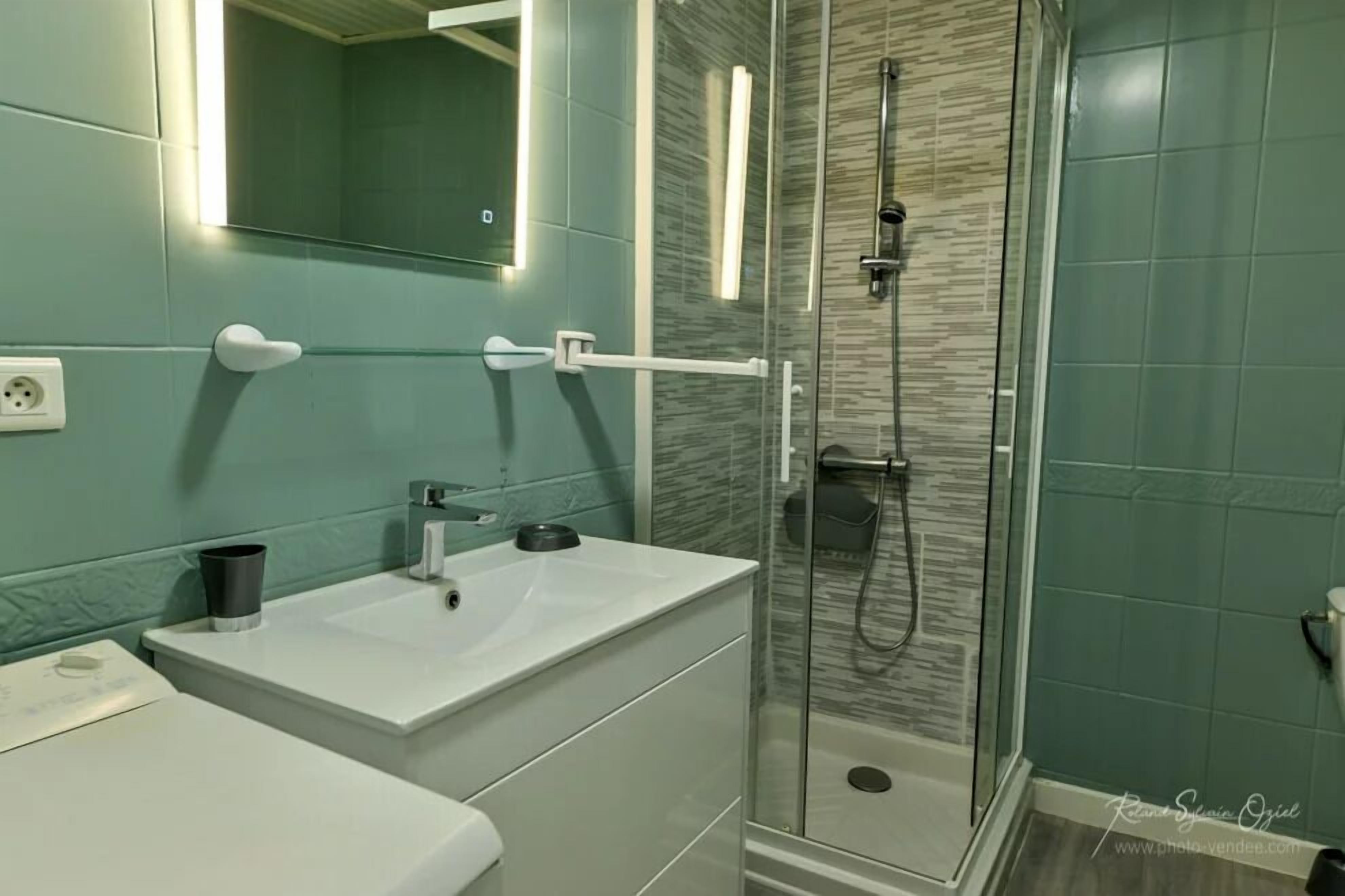 A modern bathroom with a glass-enclosed shower, a white sink, and a mirror above the sink.