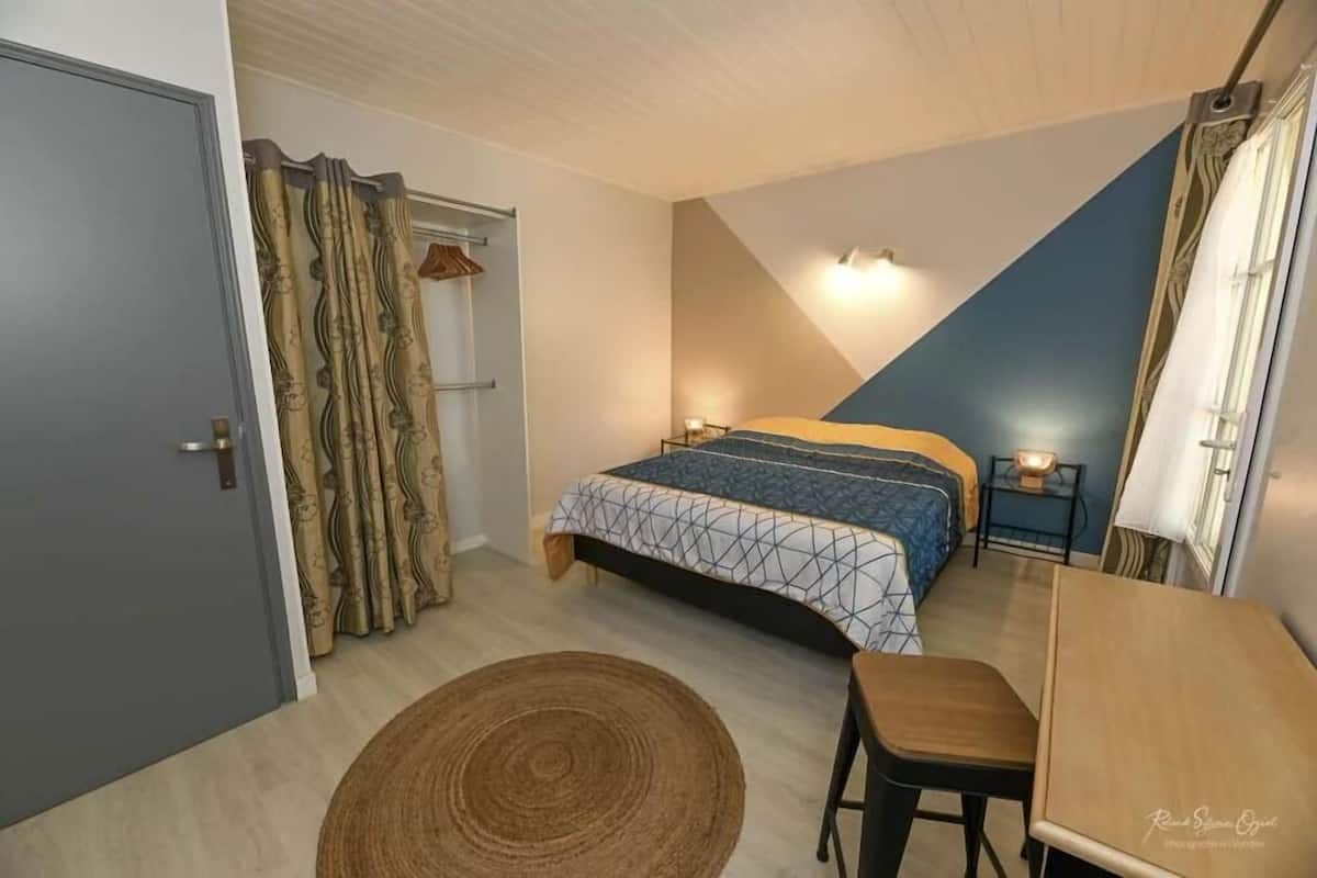 A bedroom with a bed, bedside table, and a small desk with a chair.