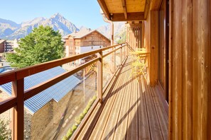 A wooden balcony with a view of mountains and a clear sky. - Base Camp Lodge Les 2 Alpes  (Les Deux Alpes)