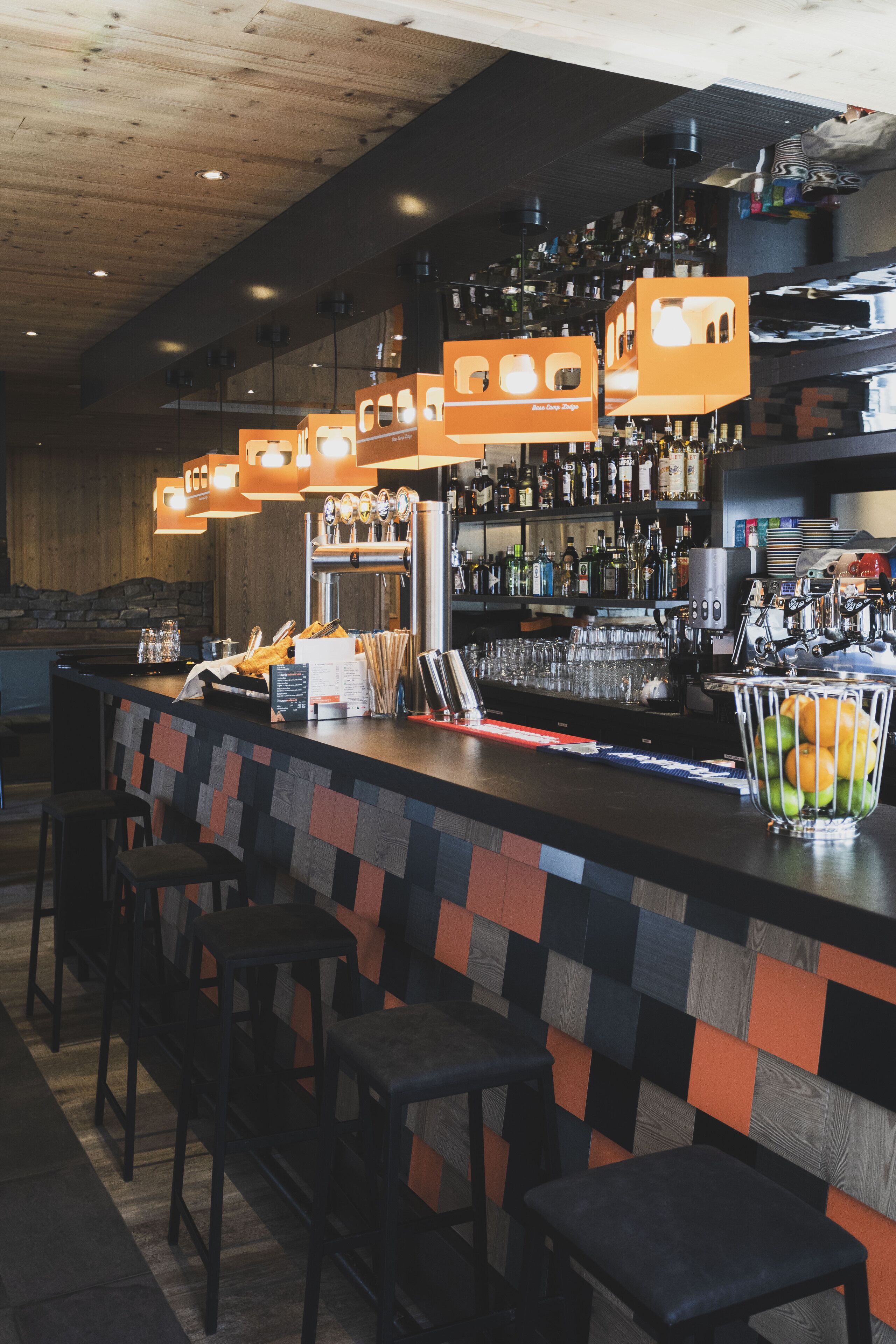 A bar area with a counter, stools, and a variety of bottles and glasses.