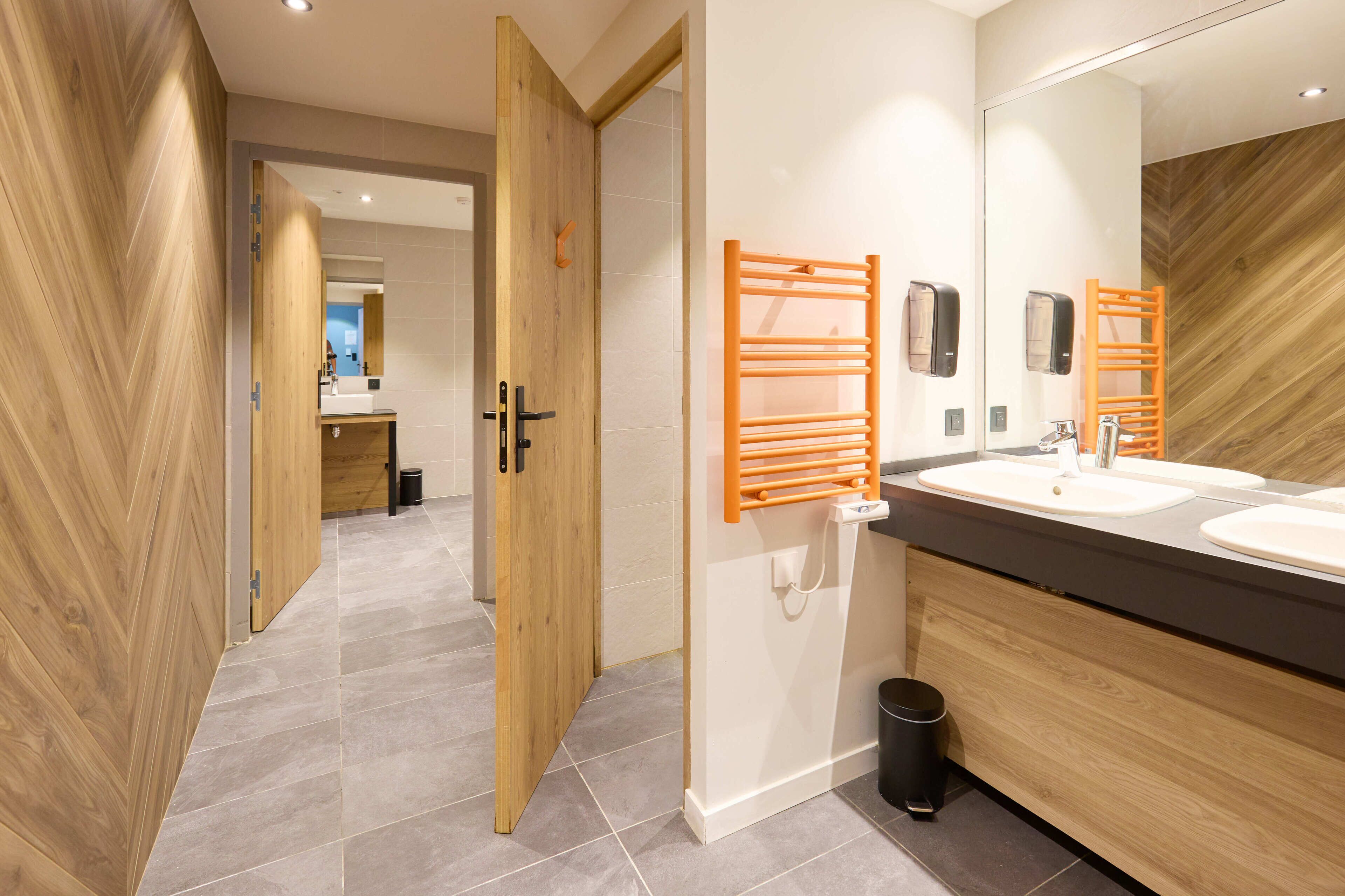 A modern bathroom with wooden accents, a large mirror, and dual sinks.