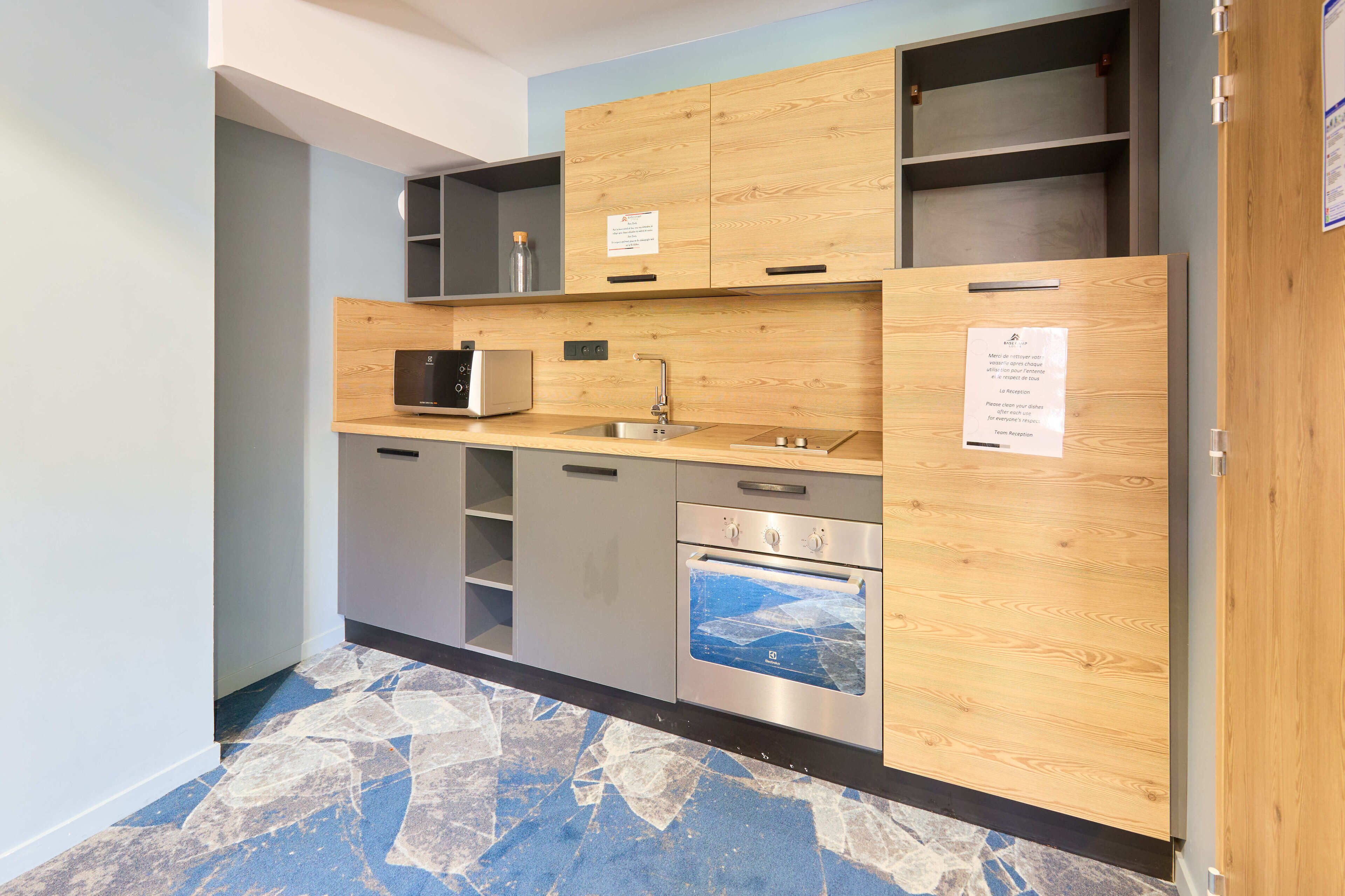 Una cucina moderna con mobili in legno, forno a microonde integrato, lavello in acciaio inossidabile e forno incassato.