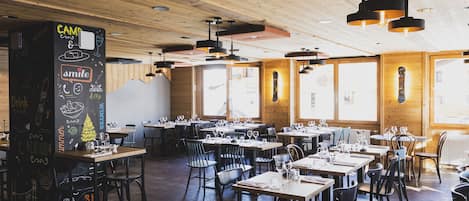 Un restaurant avec des plafonds en bois et des tables dressées pour le service.