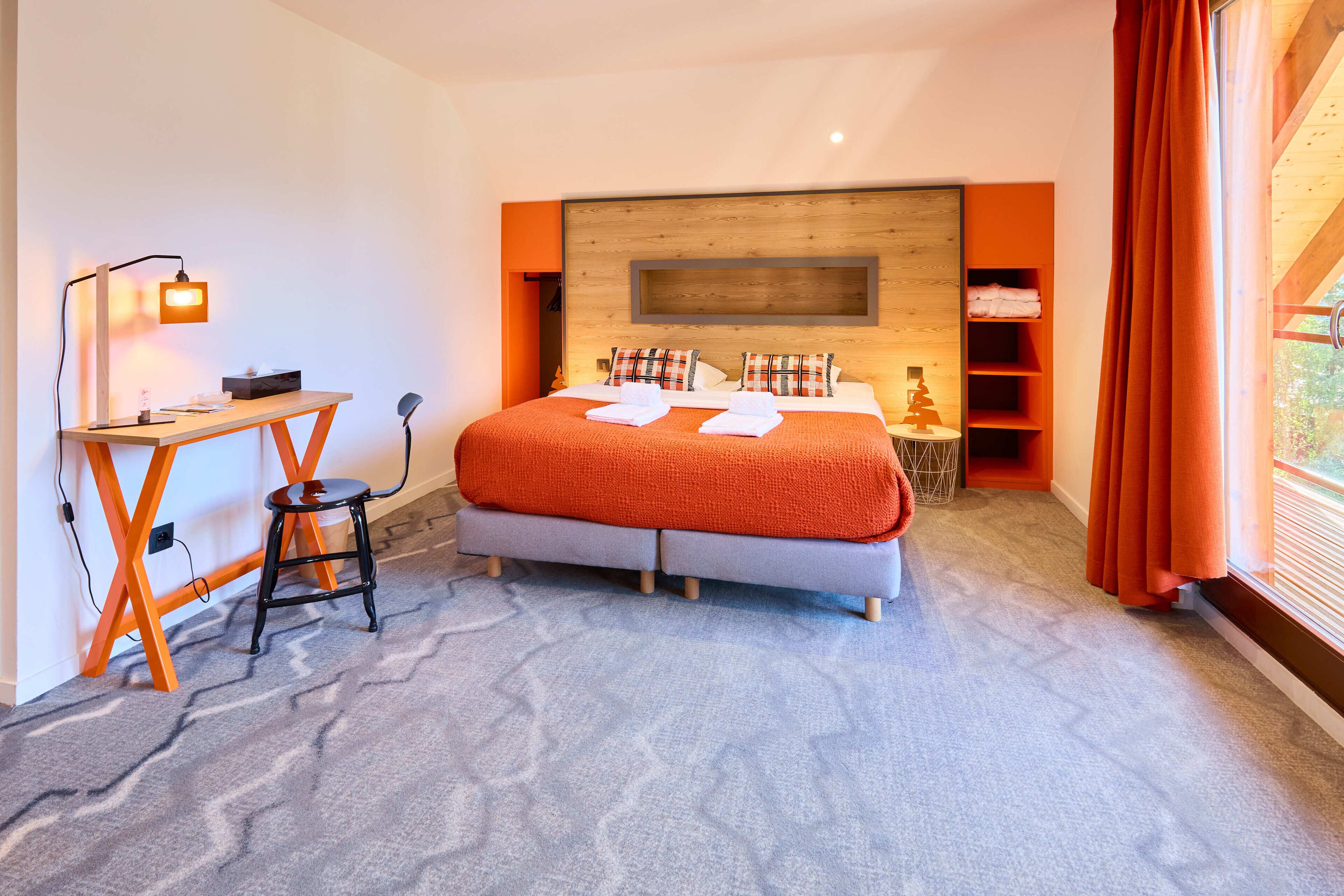 A modern bedroom with a large bed, a desk, and a chair.