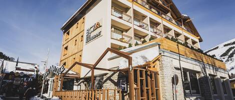 Un edificio de varios pisos con fachada de madera, balcones y el letrero de un restaurante.
