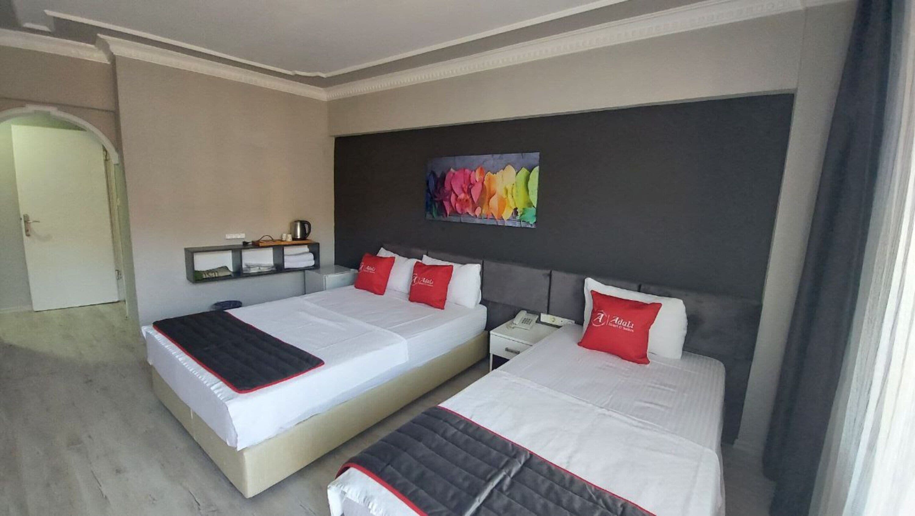 Habitación de hotel con dos camas, un cuadro en la pared y un pequeño estante con objetos.