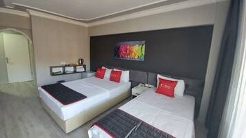 Habitación de hotel con dos camas, un cuadro en la pared y un pequeño estante con objetos.