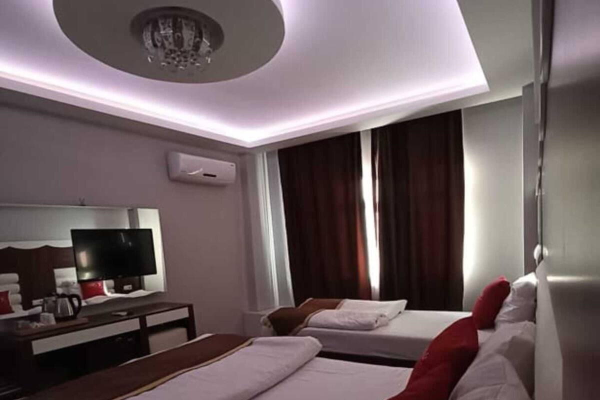 A hotel room with a bed, a desk with a television, and a ceiling light fixture.