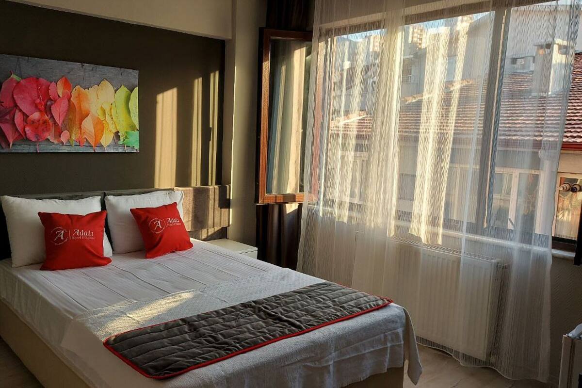 A bed with a quilted cover, two pillows, and a painting above it.