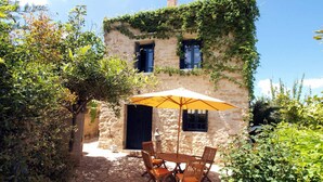 A stone building with ivy-covered walls, a wooden table with chairs, and a yellow umbrella. - ★ Only for 2 ★ cosy stone villa, totally private, pool, near sea, WiFi, parking (Chania)