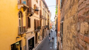 A narrow street lined with historic buildings, featuring balconies and arched windows.
