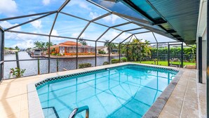 A swimming pool with a view of a canal and a house across the water. - Look at this View with direct Gulf Access (Cape Coral)
